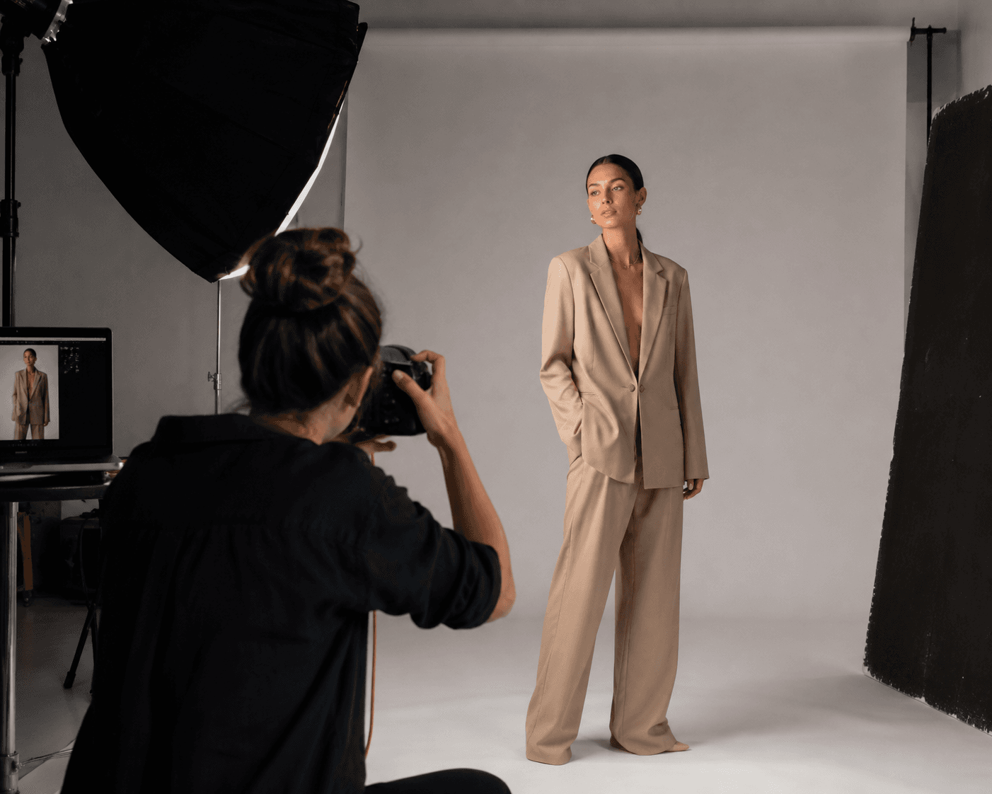 Séance mode en studio, photographe et mannequin devant un fond neutre